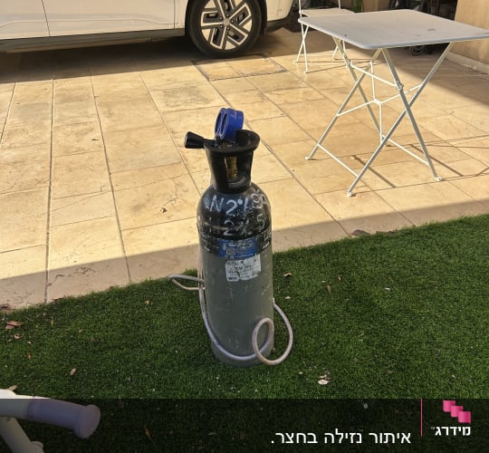 בלון גז בחצר עם רכב ושולחן מתקפל